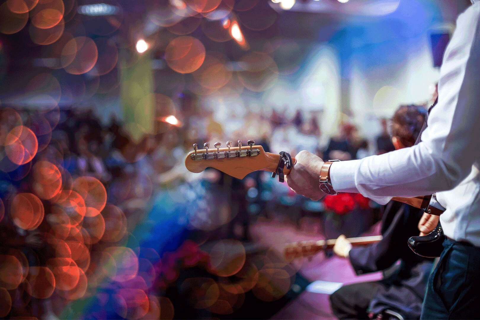 man playing guitar with a background faded audience